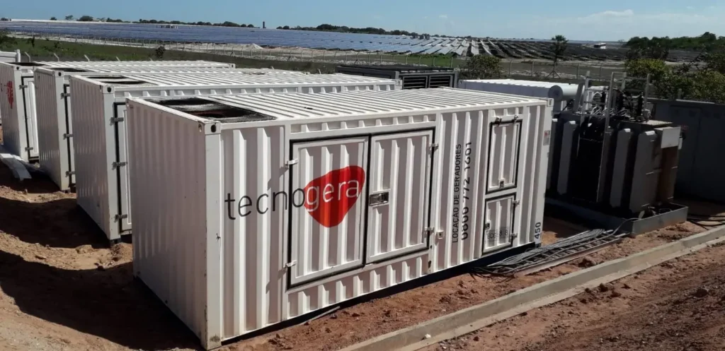 Um gerador da Tecnogera está posicionado sobre o solo, próximo a equipamentos elétricos - ilustrando uma das soluções do guia de planejamento energético e sazonalidade na indústria