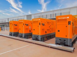 Quatro geradores laranja da Tecnogera, alinhados e prontos para uso em emergências em São Paulo.