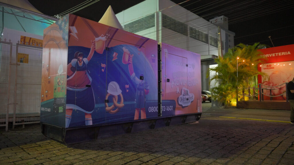 Gerador da Tecnogera, com arte colorida de operários e equipamentos, destaca soluções para grandes eventos.